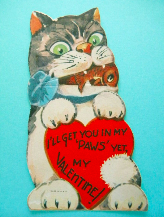 SCARY CARTOON VALENTINE CAT WITH A FISH IN ITS MOUTH. CAPTION READS: "I'LL GET YOU IN MY 'PAWS' YET, MY VALENTINE"