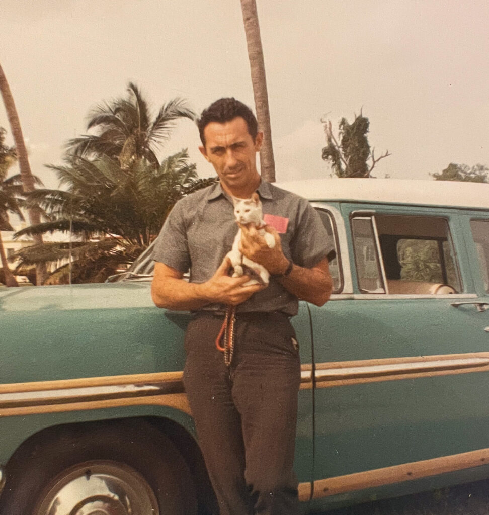 Man holding a kitten in front of a vintage 1950's car, vintage cat photo