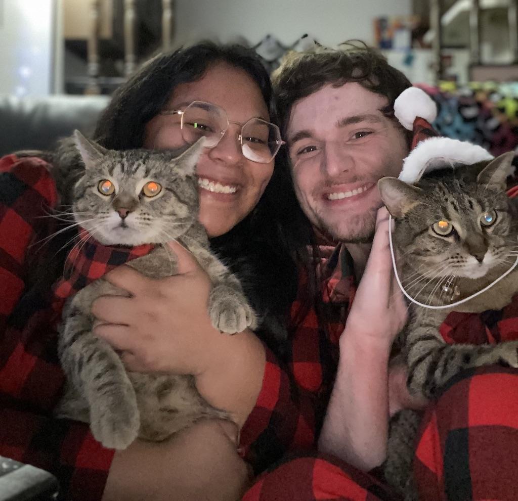 Smiling couple in matching pajamas holding cats on their laps
